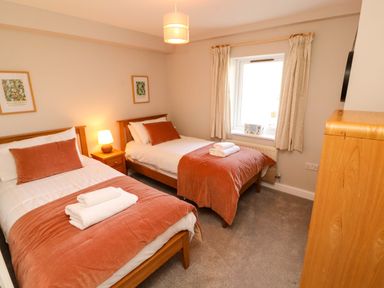 A bedroom with two beds and a window at Bramble Cottage Thornthwaite near Braithwaite