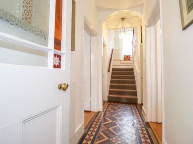 A hallway with patterned tile floor leading to carpeted stairs at Middletown in Keswick