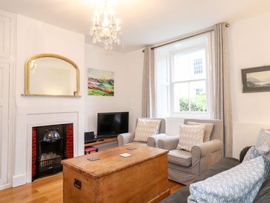 A living room with armchairs a wooden chest a small fireplace a television and a large window at Middletown in Keswick