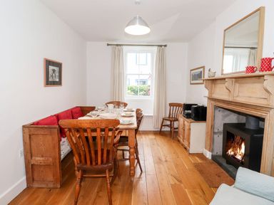 A dining room with wooden table chairs a bench a lit fireplace and window at Middletown in Keswick