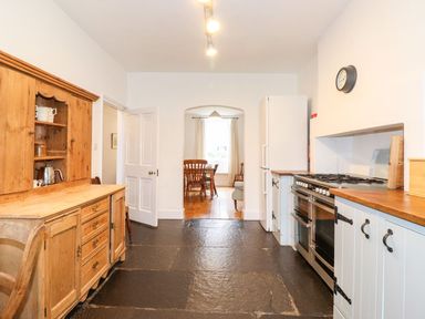 A kitchen with wooden cabinets a large stove a refrigerator and a dining area visible through an archway at Middletown in Keswick