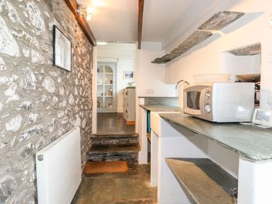 A kitchen with stone walls stone steps and a microwave on the counter at Middletown in Keswick