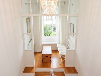 A small seating area with a wooden bench and table in front of a window with white curtains at Middletown in Keswick