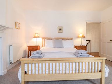 A bedroom with a wooden bed frame two bedside tables with lamps and folded towels at Middletown in Keswick