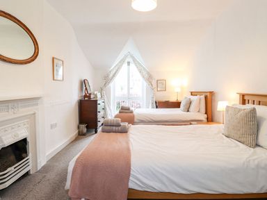 A bedroom with two single beds a dresser a fireplace and a window with curtains at Middletown in Keswick