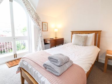 A bedroom with a wooden bed with folded towels on a pink blanket and a side table with a lamp at Middletown in Keswick