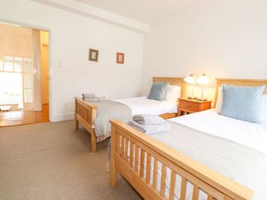A bedroom with two single wooden beds blue cushions and a bedside table with two lamps at Middletown in Keswick