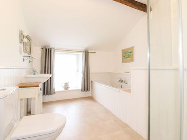 A bathroom with toilet sink bathtub window with curtains and a painting at Middletown in Keswick