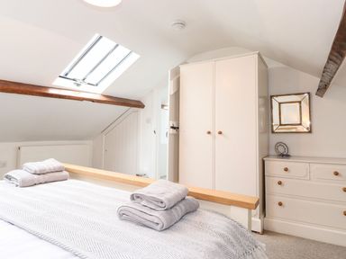 A bedroom with a skylight wooden beams a wardrobe a chest of drawers and a bed with folded towels at Middletown in Keswick