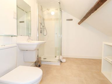 A bathroom with a toilet sink glass shower and wooden beam at Middletown in Keswick