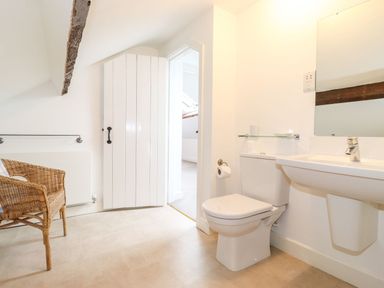 A bathroom with a toilet sink wicker chair and a white door at Middletown in Keswick