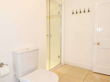 A bathroom with a toilet a glass shower door a towel hook rack and a door at Middletown in Keswick