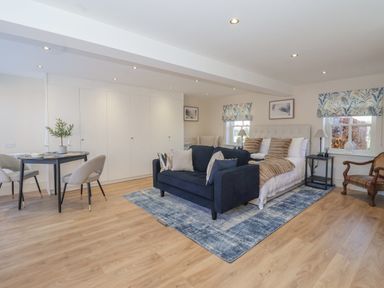 A bedroom with a navy blue sofa and bed on a blue rug near a dining table with chairs at Providence Court Near Easingwold