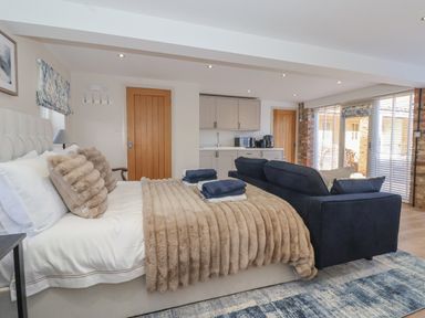 A bedroom with a bed a sofa a kitchenette and large windows at Providence Court Near Easingwold