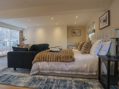 A bedroom with a bed sofa lamps and large windows at Providence Court Near Easingwold