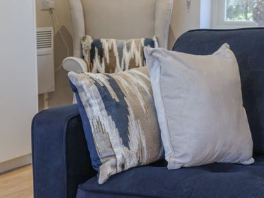 A close up of two cushions on a dark blue sofa with a beige armchair and window in the background at Providence Court near Easingwold
