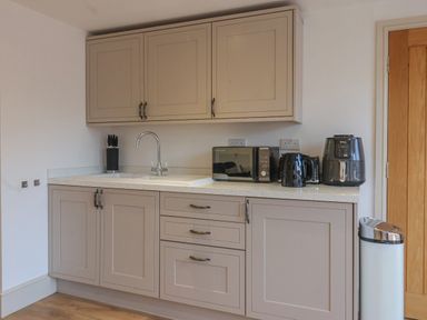 A kitchen area with beige cabinets a sink a microwave kettle air fryer knife block and a trash bin at Providence Court Near Easingwold