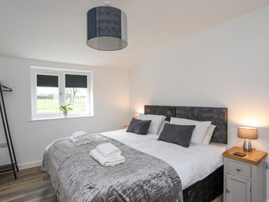 A bedroom with a double bed bedside table lamp folded towels and a window with blinds at Ynys Uchaf Near Benllech