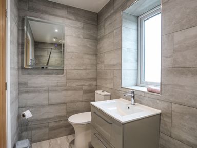 A bathroom with a sink cabinet a toilet a mirror and a window at Ynys Uchaf Near Benllech