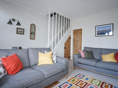 A living room with two gray sofas with colored cushions and a patterned rug at Gwelfor in Harlech