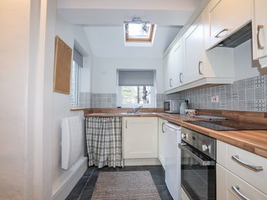 A kitchen with white cabinets wooden countertops and patterned tile backsplash at Gwelfor in Harlech