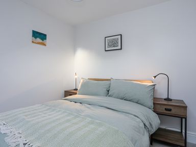 A bedroom with a double bed between two bedside tables each with a lamp and two framed pictures on the walls at Gwelfor in Harlech