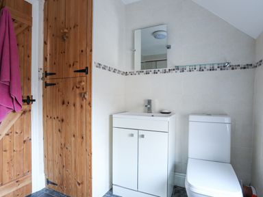 A bathroom with a white sink cabinet a mirror a toilet and wooden doors at Gwelfor in Harlech