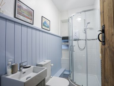 A bathroom with a shower enclosure sink toilet and framed pictures at Gwelfor in Harlech