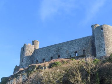 An old stone castle on a hill with round towers and small windows at Gwelfor in Harlech