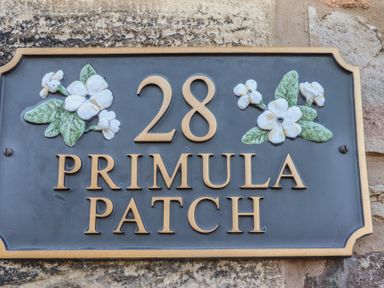 A house number plaque with the number 28 and the words Primula Patch with flower decorations at Primula Patch in Akeld near Wooler