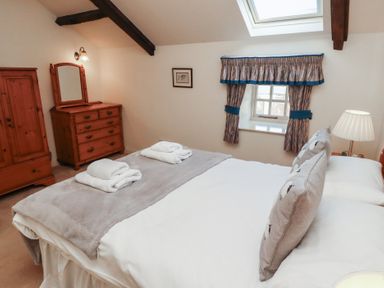 A bedroom with a bed folded towels wooden dresser wardrobe window with curtains and skylight at Primula Patch in Akeld near Wooler