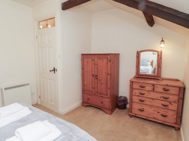 A bedroom with a wooden wardrobe a wooden dresser with mirror and a bed with towels at Primula Patch in Akeld near Wooler