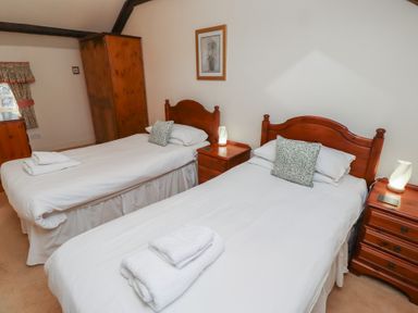 A bedroom with two single beds wooden furniture and folded towels at Primula Patch in Akeld near Wooler