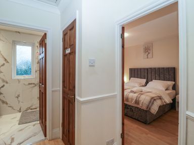 A hallway leading to a bathroom with marble tiles and a bedroom with a double bed at Hilltop Cottage in Paignton