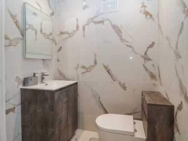 A bathroom with a sink vanity, a mirror, and a toilet at Hilltop Cottage in Paignton