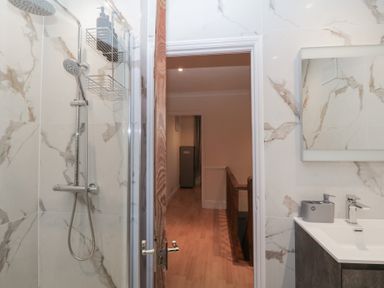 A bathroom with a shower area and a sink with a mirror at Hilltop Cottage in Paignton