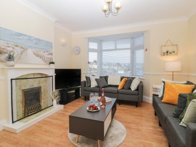 A living room with two gray sofas a coffee table a fireplace and a television at Hilltop Cottage in Paignton