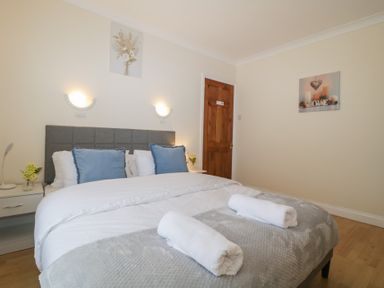 A bedroom with a bed with blue pillows and rolled towels at Hilltop Cottage in Paignton