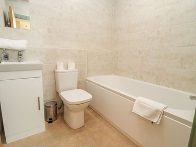 A bathroom with a bathtub toilet sink and small mirror at Bears Court Barn 1 Little Rissington near Bourton-On-The-Water