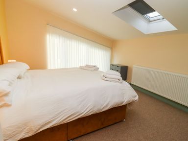 A bedroom with a bed with white bedding and folded towels a skylight window a radiator and a small cabinet with drawers at Bears Court Barn 1 Little Rissington near Bourton-On-The-Water