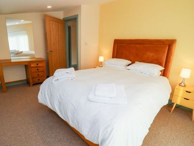 A bedroom with a bed with white bedding and two bedside tables with lamps at Bears Court Barn 1 Little Rissington near Bourton-On-The-Water