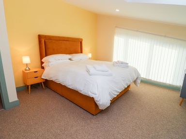 A bedroom with a double bed with white bedding and two bedside tables with lamps at Bears Court Barn 1 Little Rissington near Bourton-On-The-Water