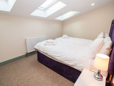 A bedroom with a double bed white bedding bedside table with lamp and skylight windows at Bears Court Barn 1 Little Rissington near Bourton-On-The-Water