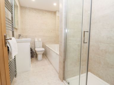 A bathroom with a shower enclosure a bathtub a toilet and a sink with a towel on a radiator at Bears Court Barn 1 in Little Rissington near Bourton-On-The-Water