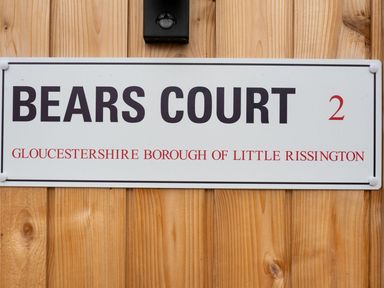 A sign on a wooden wall showing Bears Court 2 Gloucestershire Borough of Little Rissington