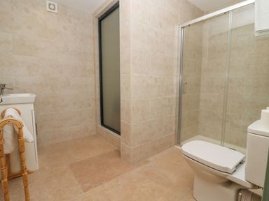 A bathroom with a toilet a sink a wooden towel rack and a glass shower enclosure at Bears Court Barn 2 Little Rissington near Bourton-On-The-Water