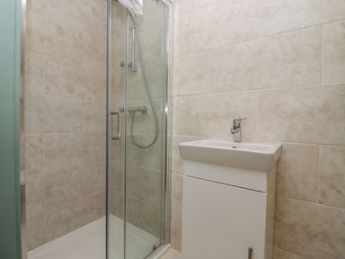 A bathroom with a glass shower enclosure and a white sink with cabinet at Bears Court Barn 2 Little Rissington near Bourton-On-The-Water