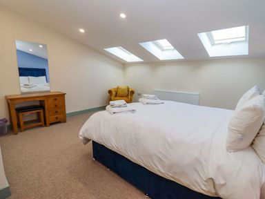 A bedroom with a bed a wooden desk with mirror a chair and skylights at Bears Court Barn 2 Little Rissington near Bourton-On-The-Water