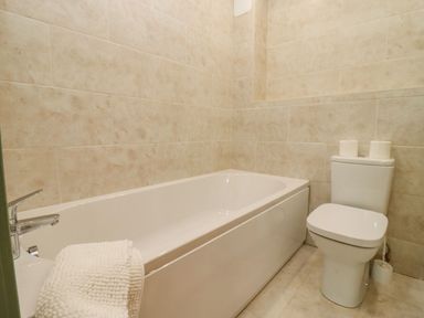 A bathroom with a bathtub and a toilet with two toilet rolls on top at Bears Court Barn 2 Little Rissington near Bourton-On-The-Water