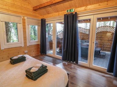 A bedroom with a bed and folded towels near windows and glass doors with dark curtains at Drumrane Lodge in Dungiven Londonderry